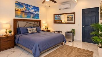 Een slaapkamer met een bed, nachtkastjes, een plafondventilator, een wandairconditioner, een deur en een groot raam met uitzicht.
