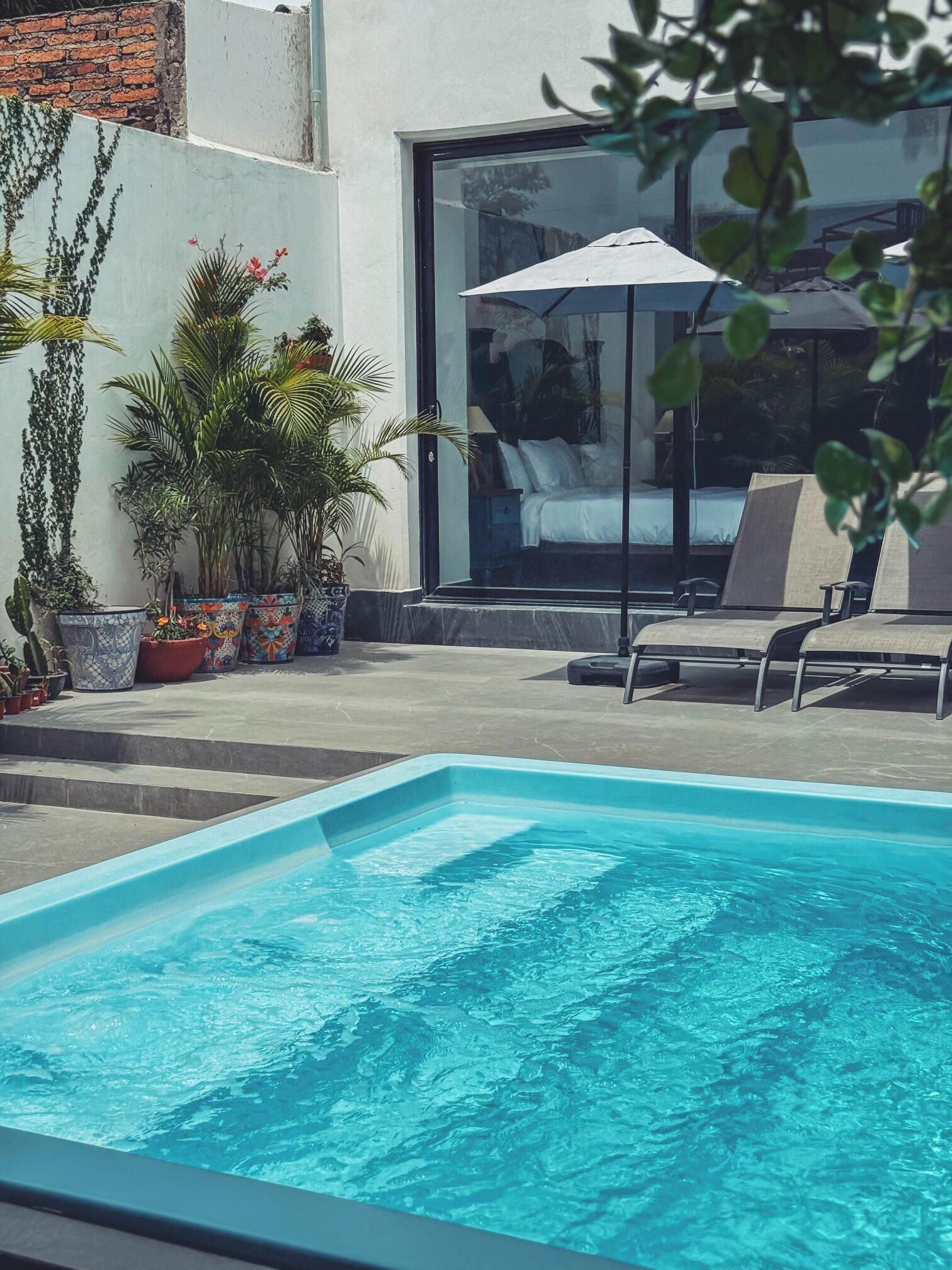 Una piscina con lettini e piante in vaso.