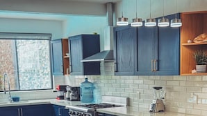 Una cocina moderna con armarios azul oscuro, encimera de mármol y una isla integrada con asientos.