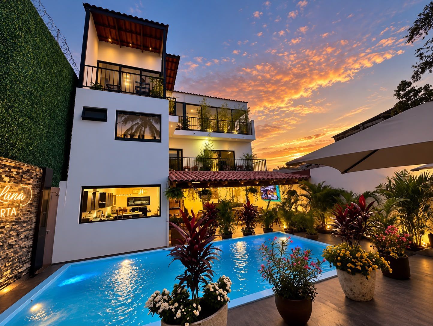 Un edificio moderno de dos pisos con piscina, asientos al aire libre y vista al atardecer.