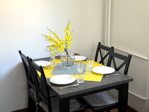 A dining table set with plates, glasses, and a vase with yellow flowers. - Warsaw Praga Apartment — Balcony & Metro Nearby (Warszawa)