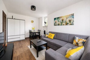 Ein modernes Wohnzimmer mit einem grauen Sofa, einem Couchtisch und einem Essbereich mit Stühlen und einem Tisch.