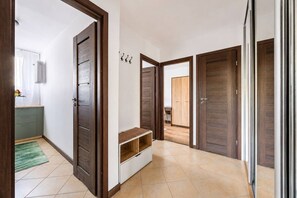 A hallway with wooden doors, a bench, and a small table with a vase of flowers. - Warsaw Praga Apartment — Balcony & Metro Nearby (Warszawa)