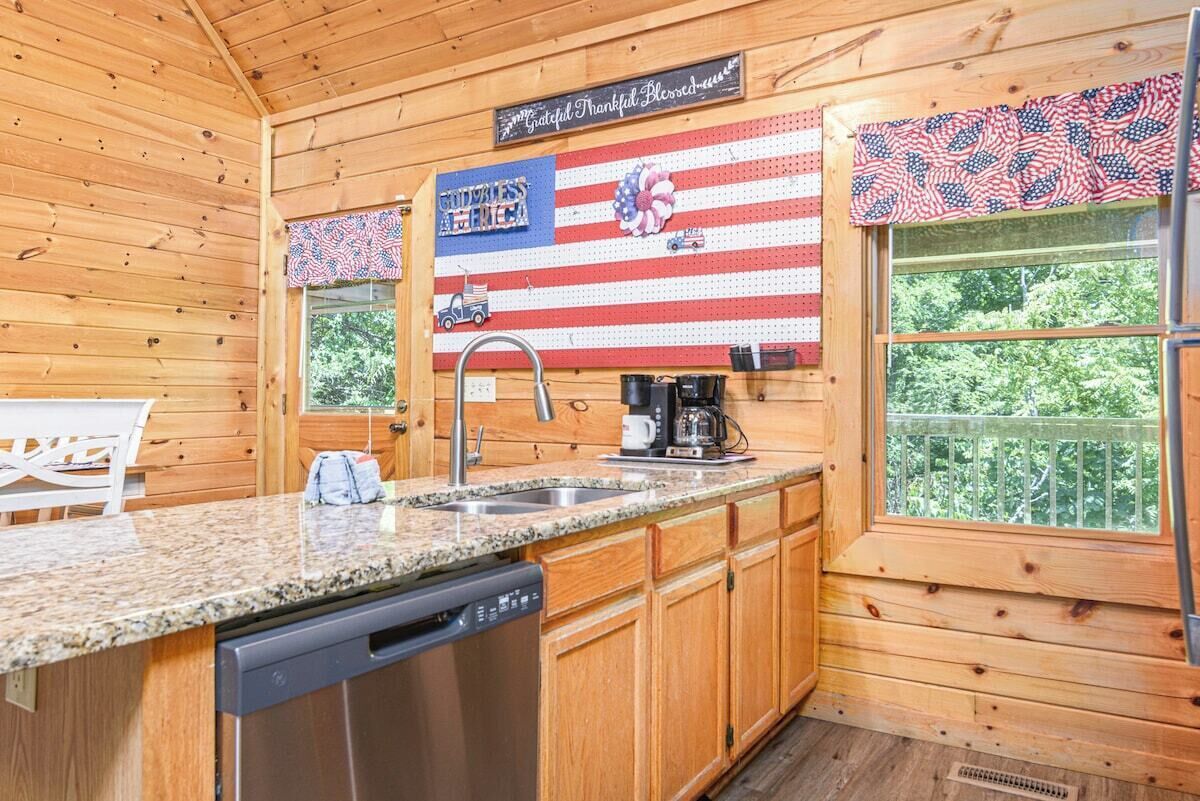 A kitchen with wooden walls, a granite countertop, a dishwasher, and a coffee maker.