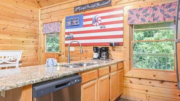 A kitchen with wooden walls, a granite countertop, a dishwasher, and a coffee maker.