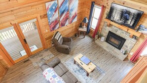A cozy cabin interior with a fireplace, a sofa, a coffee table, and a television. - Douglas Lake Cabin | Hot Tub | Sleeps 7 (Sevierville)