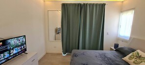 Ein Schlafzimmer mit einem Bett, einem Fernseher, einem Fenster mit Blick und einem Vorhang.