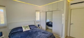 A bedroom with a bed, a wardrobe, a mirror, and a door. - Modern 1BR Sosúa Ocean Village 100 Mbps Wi-Fi (Sosúa)