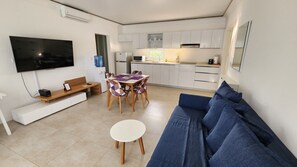 A compact living space with a kitchenette, a dining area, a sofa, and a flat-screen TV. - Modern 1BR Sosúa Ocean Village 100 Mbps Wi-Fi (Sosúa)