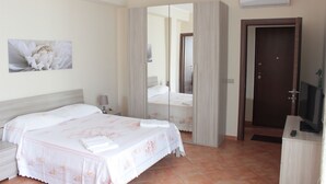 Een hotelkamer met een bed, nachtkastje, televisie en een deur.