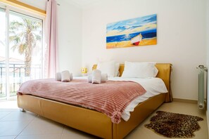 Ein Schlafzimmer mit einem Bett, Kissen, einem Bild mit Strandmotiv, einer Heizung und einem Leopardenfellteppich.