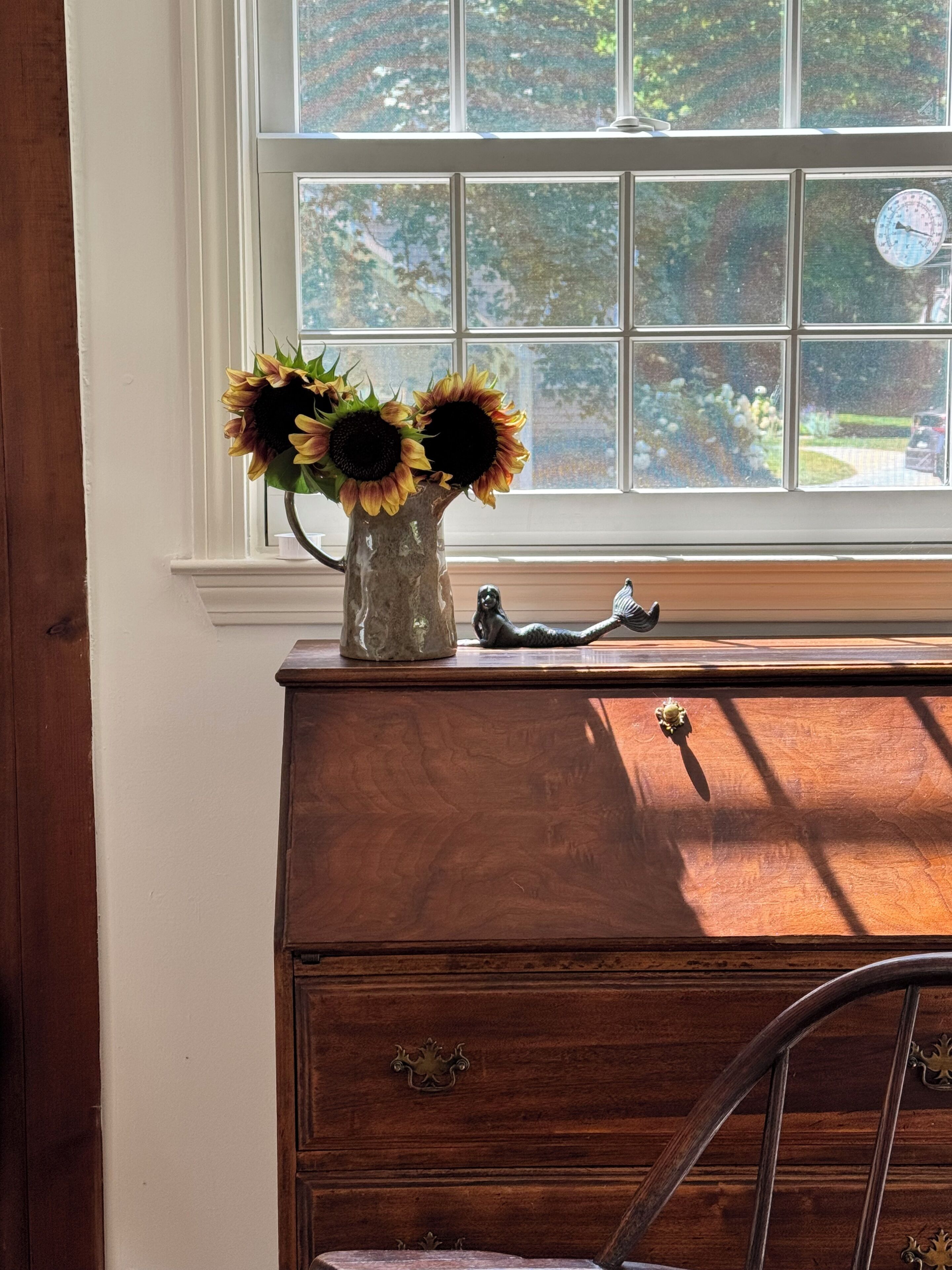 A wooden dresser with a vase of sunflowers and a figurine.