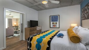 Una camera d'albergo con un letto, una televisione, un comò e una ventola a soffitto.