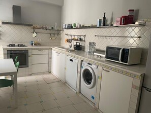 Eine kompakte Küche mit Waschmaschine, Mikrowelle und einer kleinen Essecke mit einem Stuhl.