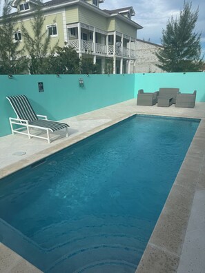 A swimming pool with a lounge chair and a set of wicker chairs. - Terrific 4-bedroom townhome with AC in sunny Nassau (Nassau)