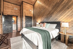 A bedroom with a wooden ceiling, a bed with pillows, a bedside table with a lamp, and a chair. - Sleeps 10, Hot Tub, Fire Pit, Arcade Game Room, 15 Min to Dollywood (Sevierville)