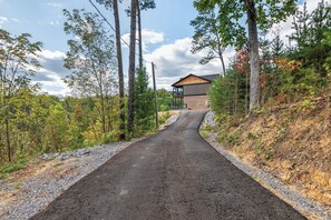 A pathway leading to a wooden cabin with a balcony, surrounded by trees and a clear sky. - Sleeps 10, Hot Tub, Fire Pit, Arcade Game Room, 15 Min to Dollywood (Sevierville)