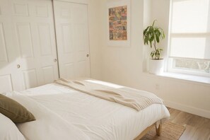 A bedroom with a bed, a window with a plant, and a door. - Modern 3 Bedroom house in Sacramento w/ Private Sauna (Antelope)