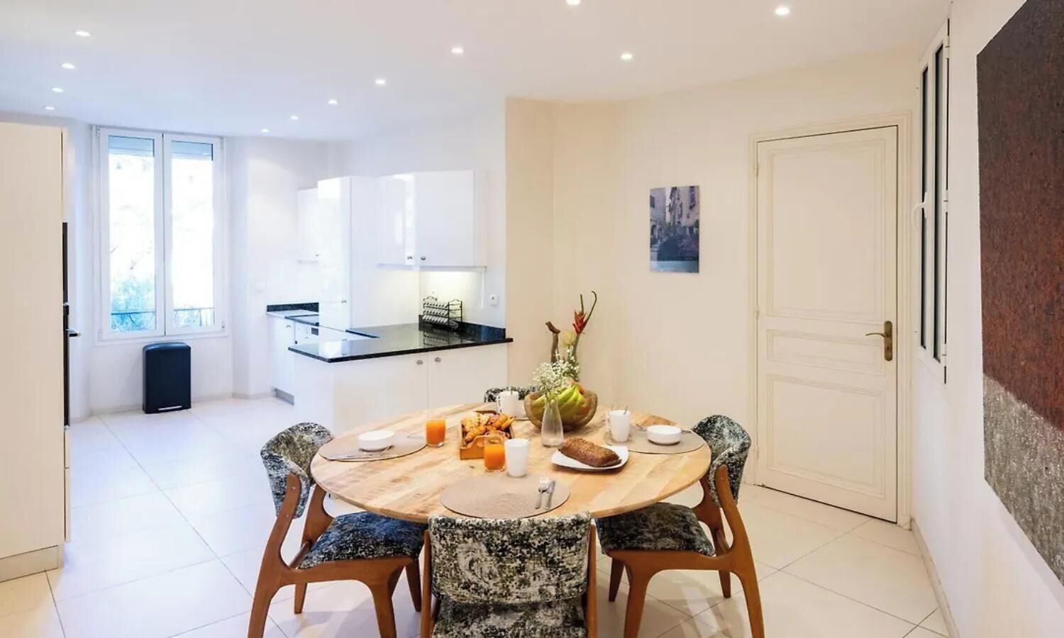 Een moderne eethoek met een ronde tafel, stoelen en een keuken op de achtergrond.