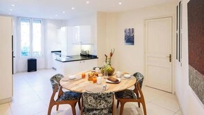 A modern dining area with a round table, chairs, and a kitchen in the background. - COMBINING TIMELESS CHARACTER WITH MODERN COMFORT IN A PRIME LOCATION (Cannes)