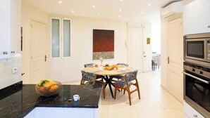 A modern kitchen with a dining area, featuring a granite countertop, a fruit bowl, and a dining table with chairs. - COMBINING TIMELESS CHARACTER WITH MODERN COMFORT IN A PRIME LOCATION (Cannes)