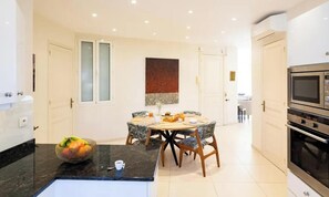 A modern kitchen with a dining area, featuring a granite countertop, a fruit bowl, and a dining table with chairs. - COMBINING TIMELESS CHARACTER WITH MODERN COMFORT IN A PRIME LOCATION (Cannes)