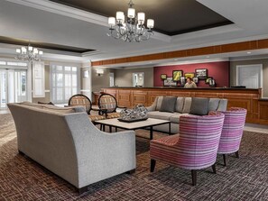 A hotel lobby with a sofa, chairs, a coffee table, a chandelier, and a reception desk. - Marriott's Fairway in New Jersey 2 Bedroom Villas (Galloway)