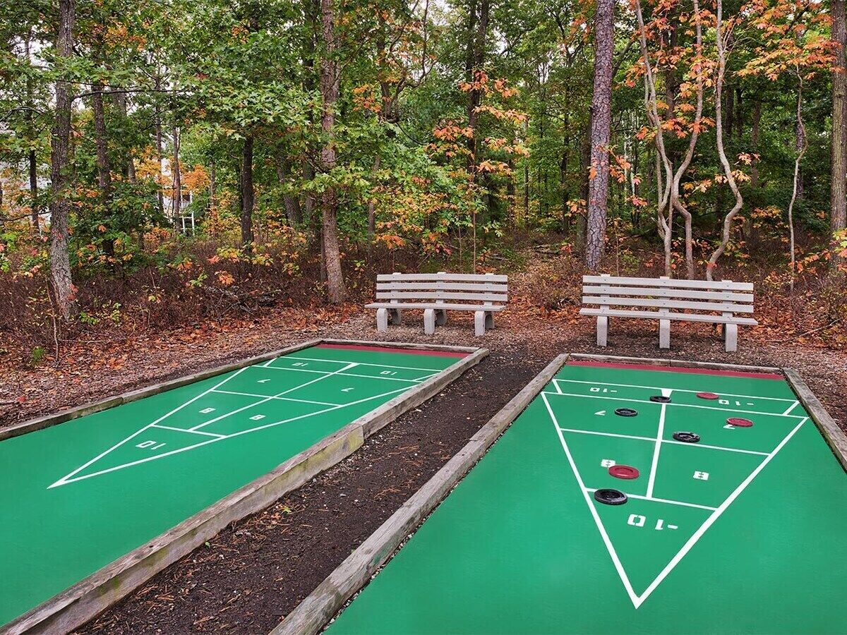 Kaksi shuffleboard-kenttää, joissa on penkkejä, puistoalueella.
