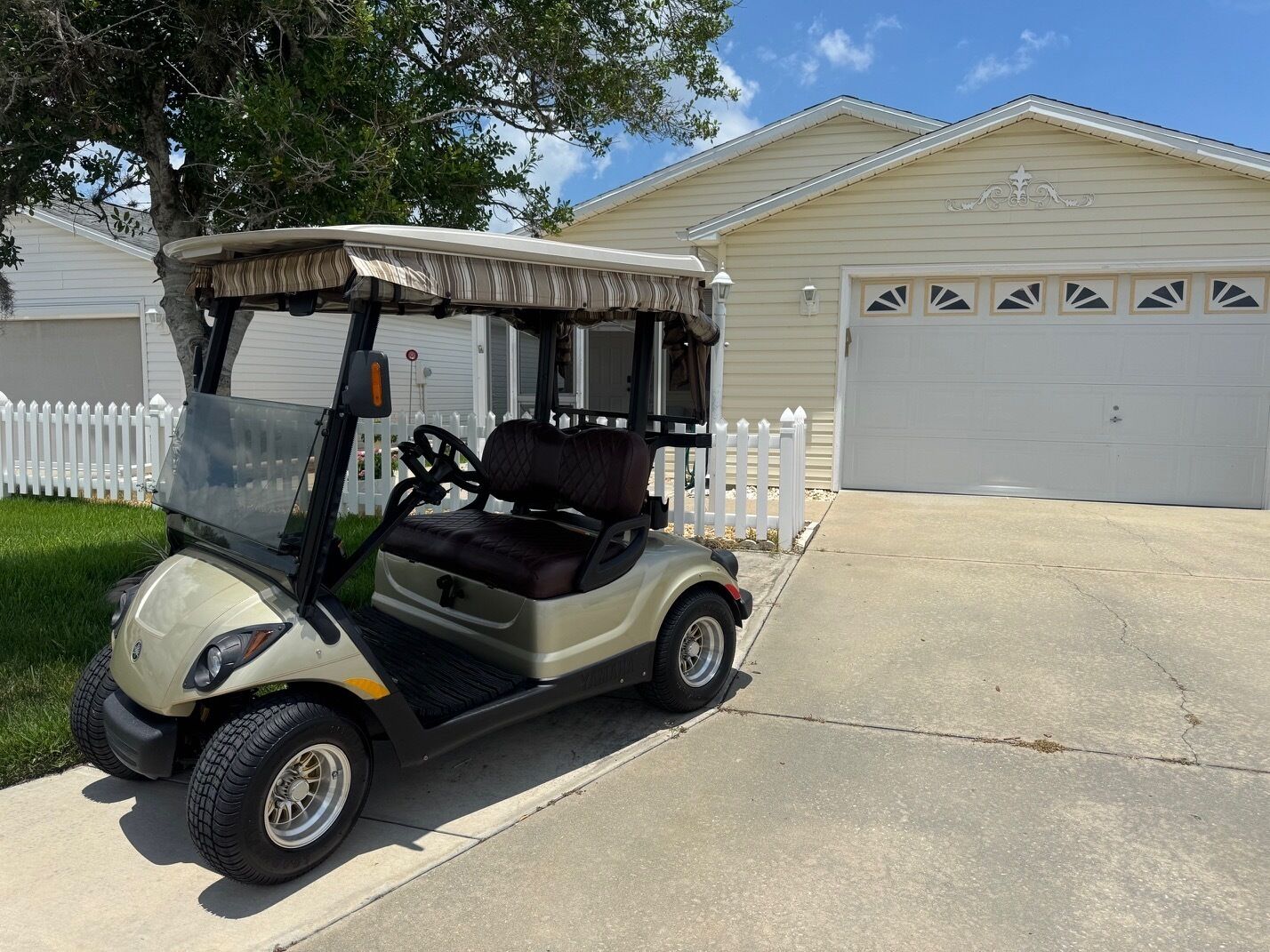Une voiturette de golf est garée devant un garage d’habitation.