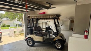 Ein Golfwagen steht in einer Garage mit weißem Zaun.