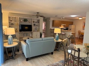 A living room with a sofa, TV, and decorative items. - Central to Spanish Springs & Lake Sumter, golf cart (Lady Lake)