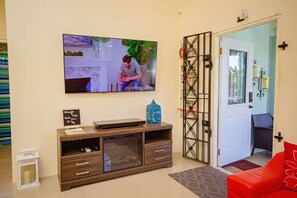 Ein Wohnzimmer mit einem an der Wand befestigten Flachbildfernseher, einer Holz-Unterhaltungsanlage, einem roten Sofa und einer Tür mit dekorativem Gitter.