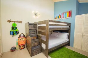 A bunk bed with a built-in desk and drawers, a green rug, and a wall with colorful artwork.