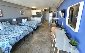 A hotel room with two beds, a kitchenette, a dining area, and a bathroom. - New Wonderful Beach Front Studio in Daytona Beach! (Daytona Beach)