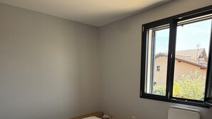 Ein Schlafzimmer mit Bett, Fenster und Heizkörper.