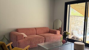 Ein modernes Wohnzimmer mit einem Ecksofa, einem Glastisch und einem gelben Sessel.
