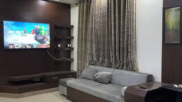 Un salon moderne avec un téléviseur à écran plat, un canapé, une table basse et un ventilateur de plafond.