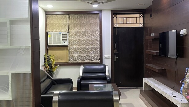 A modern hotel lobby with a reception desk, seating area, and a television mounted on the wall.