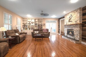 Una sala de estar con chimenea, una estantería y una zona de estar con dos sofás y una mesa de centro.