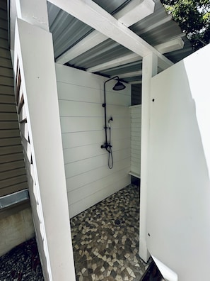 A small, enclosed shower area with a tiled floor and a showerhead.