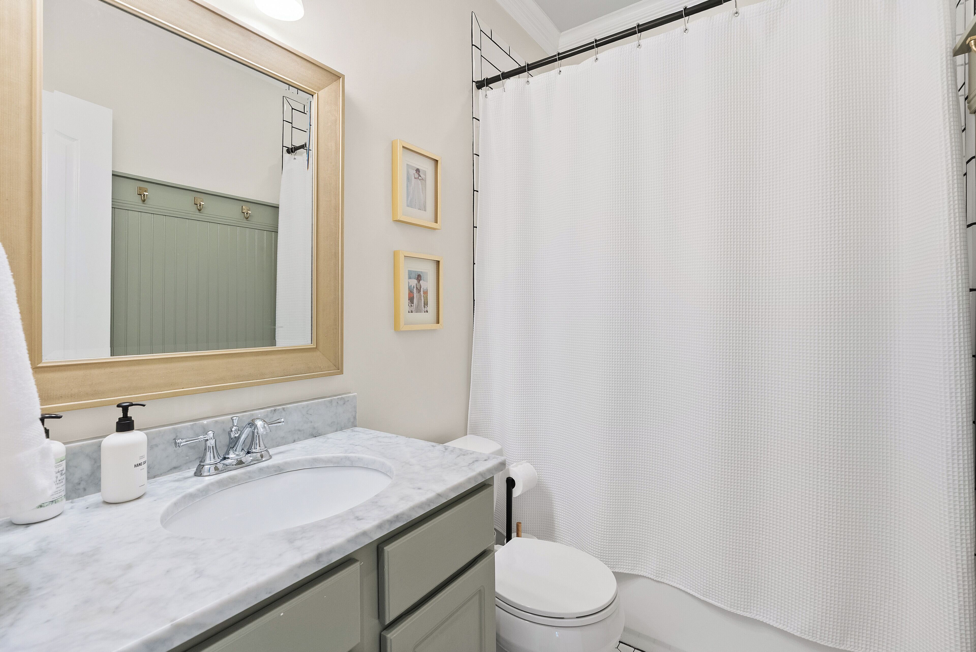 A bathroom with a white sink, a mirror, a toilet, and a shower curtain.