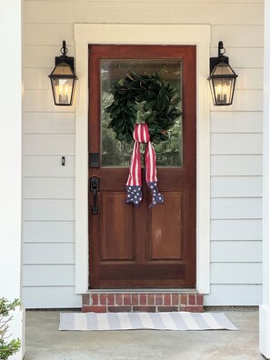 A front door with a wreath, a red and white striped scarf, and two wall-mounted lanterns. - Meet Me In Oxford- 3BR -1 Mile from the Square (Oxford)