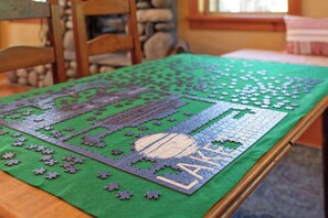 A puzzle on a green felt table with a partial view of a room. - Mountain Khaya (Truckee)
