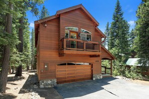 A two-story wooden cabin with a balcony, a garage, and a stone foundation. - Mountain Khaya (Truckee)