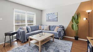 Een moderne woonkamer met een bank, salontafel en een grote plant.