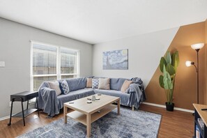 Ein modernes Wohnzimmer mit einer Couch, einem Couchtisch und einer großen Pflanze.