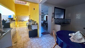 A kitchen with a dining area, a blue table, and a tiled floor. - Beach house with pool in Porto das Dunas, 8 suites, 5 min from the beach. (Aquiraz)