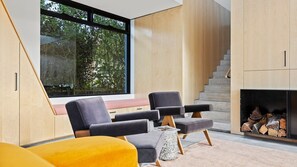 A modern living room with a large window, built-in seating, and a fireplace. - Betula - Luxury Oasis in Wallaga Lake (Wallaga Lake)