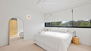 A modern bedroom with a bed, a large window, and a ceiling fan. - Betula - Luxury Oasis in Wallaga Lake (Wallaga Lake)