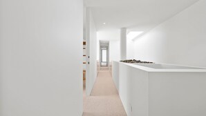 Ein moderner, minimalistischer Flur mit weißen Wänden und Teppichboden.